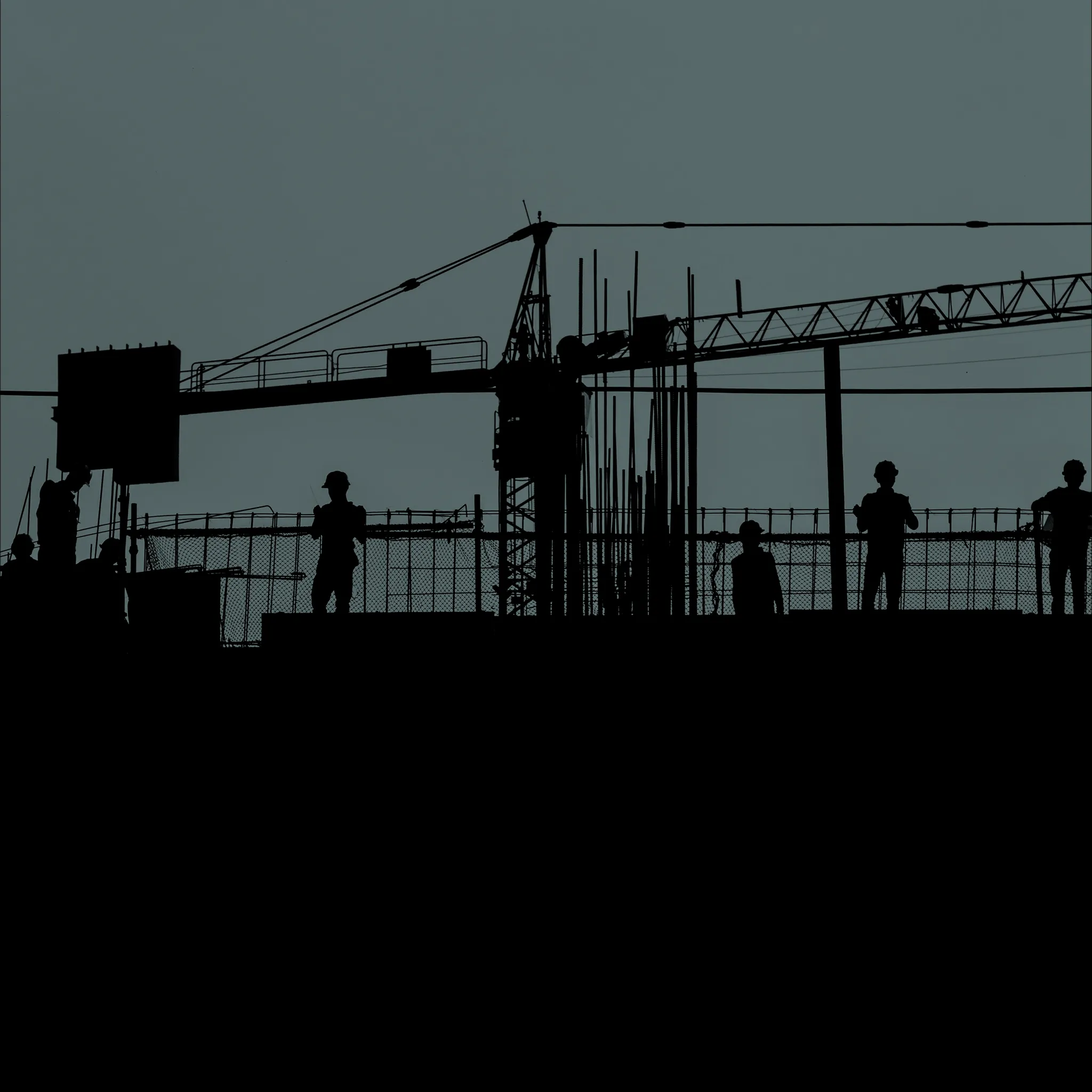 Silhouettes of construction workers and a crane at a building site against a gray sky.